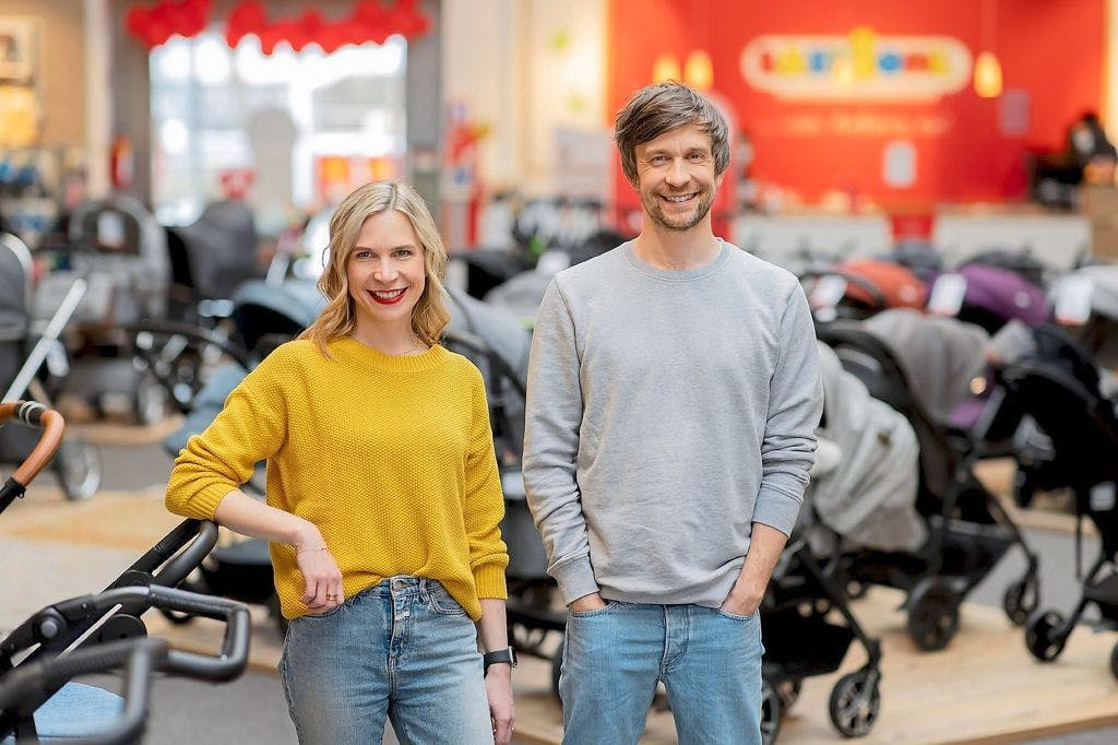 Ein mann und eine frau stehen gemeinsam neben einer baby-kutsche.