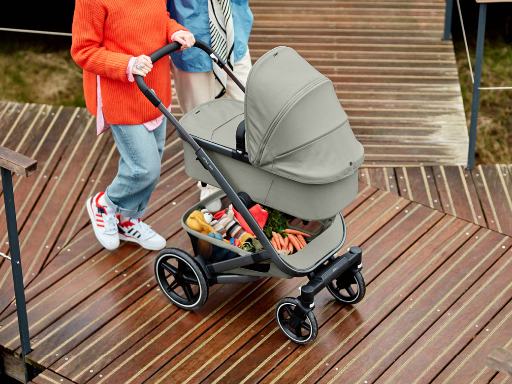 Paar schiebt den Kinderwagen Geo3 in grau von Joolz über einen Holzsteg.