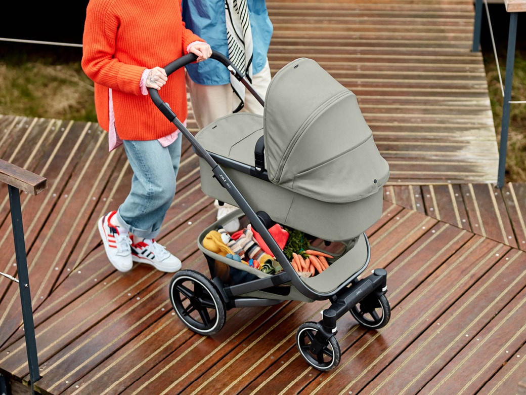 Paar schiebt den Kinderwagen Geo3 in grau von Joolz über einen Holzsteg.