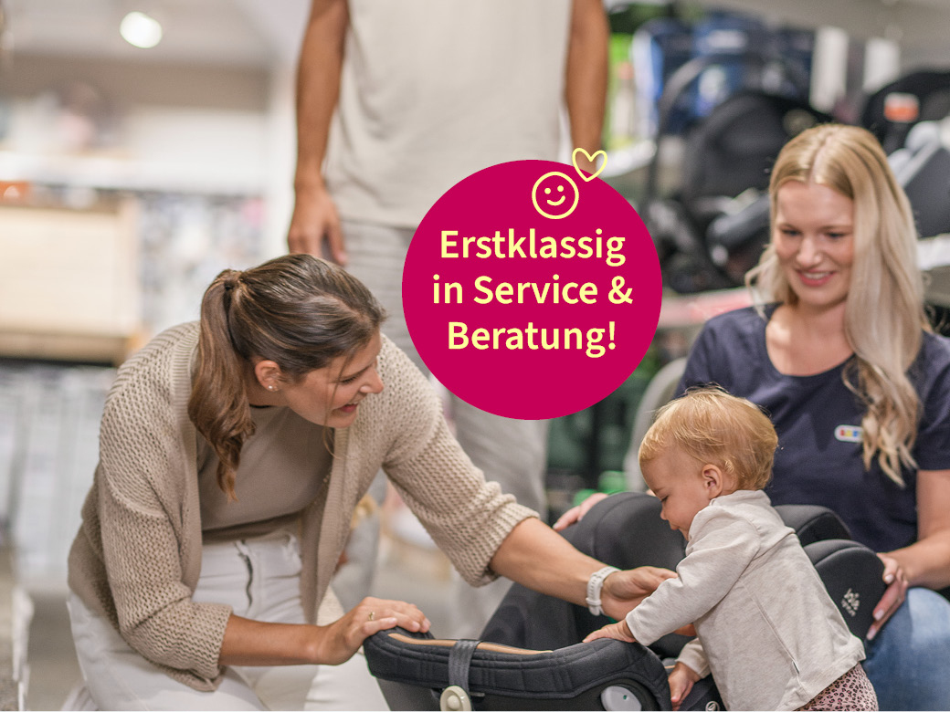 Erstklassig in Service und Beratung! Mutter sitzt mit ihrem Kind neben einem Kindersitz und einer Verkäuferin.