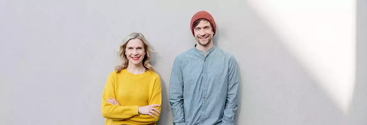 Ein mann und eine frau stehen gemeinsam vor einer weißen wand.