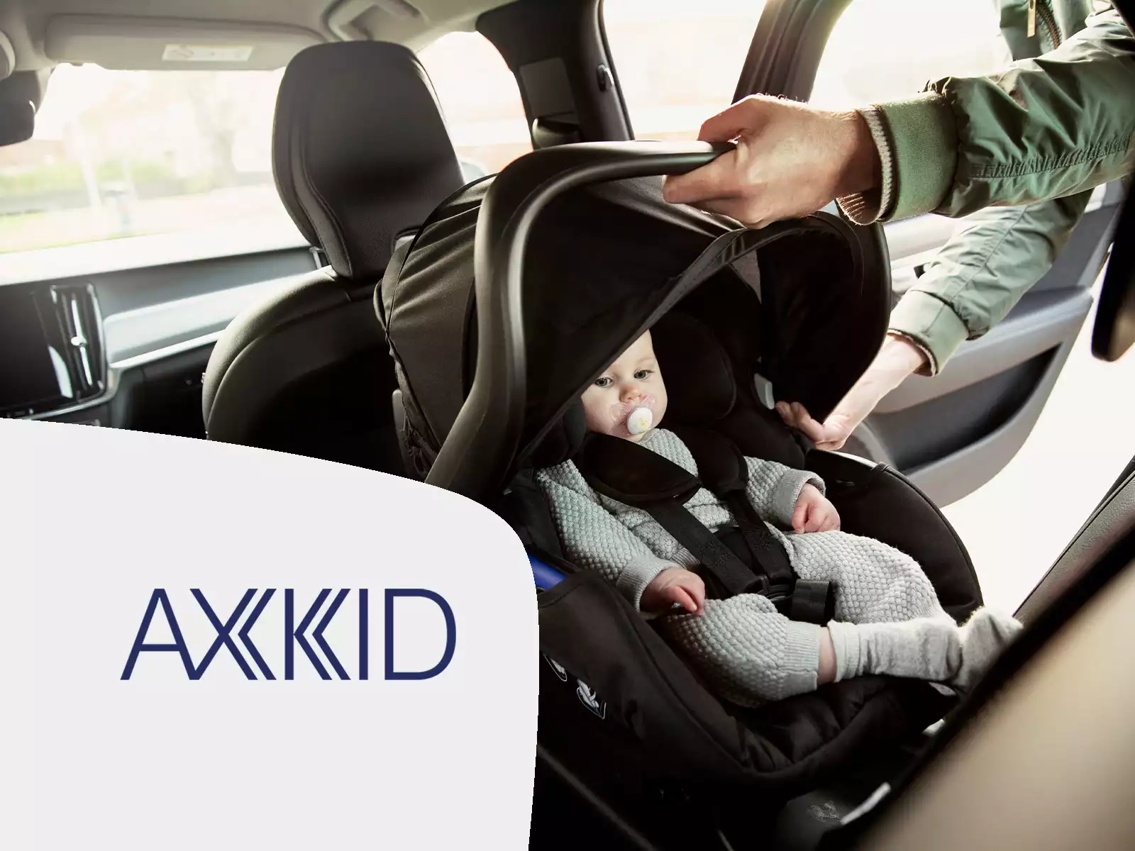 Ein mann, der ein baby auf einem autositz hält.