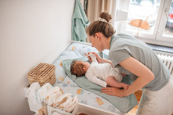 Eine frau, die ein baby in einer krippe hält.