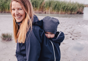 Eine frau, die ein kind auf dem rücken trägt.