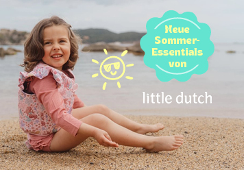 Mädchen mit Badeshirt und Schwimmweste sitzend am Strand. Neue Sommer Essentials von little dutch.
