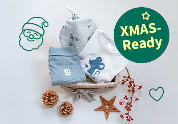 XMAS-Ready: Babymode zum Fest liegend zwischen Sternen und Tannenzapfen abgebildet.