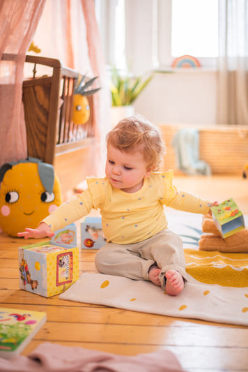 Baby ein, das auf dem boden sitzt und mit spielzeug.