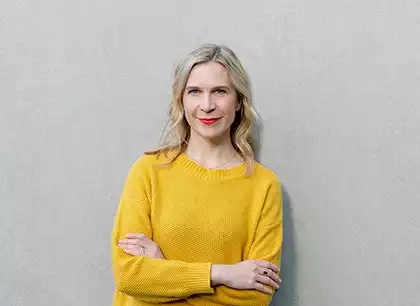 Eine frau in einem gelben pullover, die gegen eine graue.