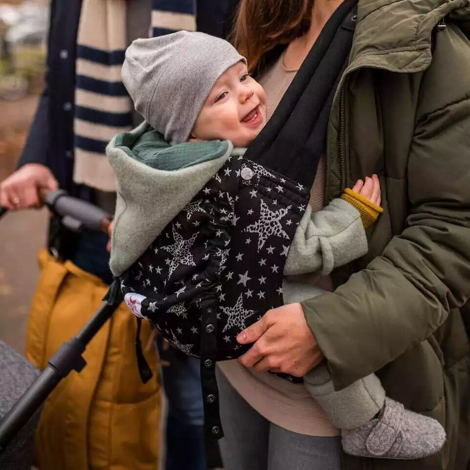 Eine frau, die ein baby in einem träger hält.
